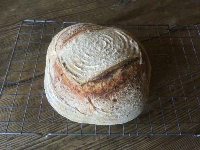 A loaf of homemade bread cooling on a rack